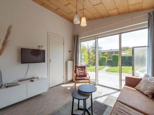 a living room with a couch and a tv and a table at Bungalow in Callantsoog near Sandy Beach in Callantsoog