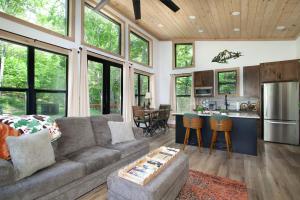 a living room with a couch and a kitchen at Smoky Mountain Dove | Hot Tub, Firepit, Fireplace in Sevierville