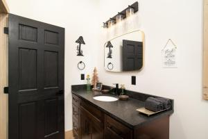 a bathroom with a sink and a mirror and a black door at Smoky Mountain Dove | Hot Tub, Firepit, Fireplace in Sevierville +23 photos