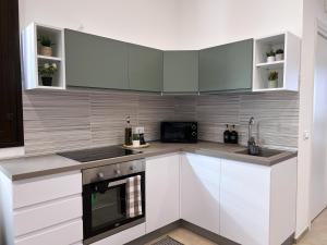 a kitchen with white cabinets and a black oven at Appartamenti Fiore in Paceco