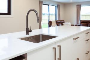 Una cocina con fregadero de acero inoxidable y gabinetes blancos. en Memorial Crescent Retreat - 4 bedroom family home, en Methven