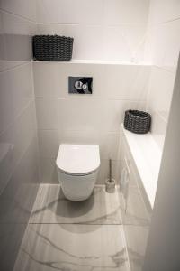 a white bathroom with a toilet and two baskets at White Apartment in Liepāja