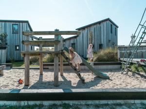 two children playing on a slide in a playground at Kidz Lodge in Zon Zee Strand with Play Area in Callantsoog +15 photos