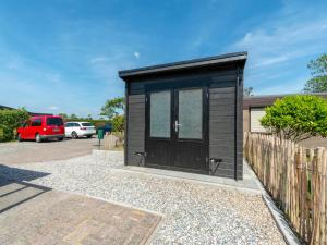 a black tiny house in a parking lot at Bungalow in Callantsoog near the Beach in Callantsoog
