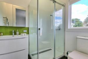a bathroom with a glass shower and a toilet at Spacious Remuera Bungalow with Parking and Aircon in Auckland +26 photos
