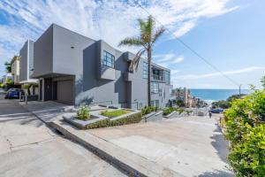a white building with a palm tree in front of the ocean at Stunning Panoramic Ocean Views Penthouse Hot Tub in Manhattan Beach