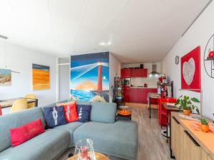Una sala de estar con un sofá azul y una cocina. en Apartment by Dutch Dunes and Sea, en Julianadorp