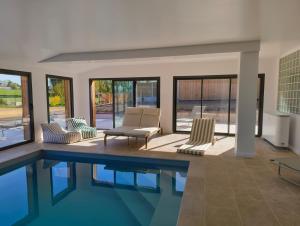 a house with a swimming pool and chairs and windows at LES PATICHERES - La Grange avec accès à la piscine in Biville-la-Baignarde