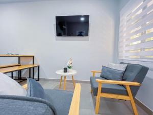 ein Wohnzimmer mit 2 blauen Stühlen und einem TV in der Unterkunft Forest apartments studio F1, walking to the beach in Jacó