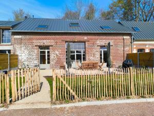 a brick house with a fence in front of it at LES PATICHERES - La Grange avec accès à la piscine in Biville-la-Baignarde