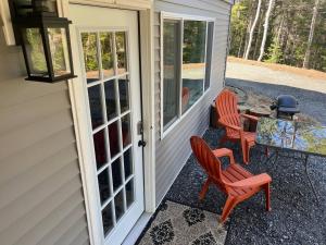 a patio with two chairs and a table on a house at Waterfront In Law Suite on Wolf Pond in Lake Placid