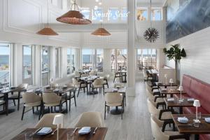 a restaurant with tables and chairs and windows at South Seas Resort - Official Site in Captiva
