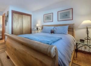 Schlafzimmer mit einem großen Holzbett mit blauer Bettwäsche in der Unterkunft Serene Condo by Palisades Base and Golf Course in Olympic Valley + 60 Fotos