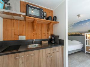 a kitchen with a sink and a tv on a wall at Chalet in Texel near Beach and Forest in Sint Maartenszee