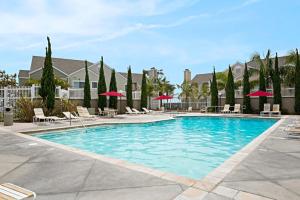 een zwembad in een resort met stoelen en parasols bij Chic Upstairs Condo Steps from Strands Beach in Dana Point