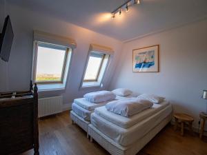 two beds in a room with two windows at Penthouse Duinerei by the sea with sauna in Callantsoog