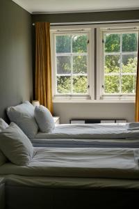 two beds in a room with two windows at Hald Bed and Breakfast in Mandal