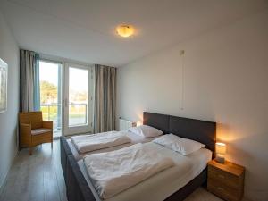 Un dormitorio con dos camas y una gran ventana. en Apartment in Groote Keeten near Sandy Beach, en Callantsoog