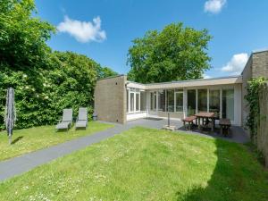 a garden with two chairs and a table and a building at Bungalow in Sint Maartenszee near Beach in Sint Maartensvlotbrug