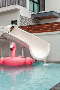 a water slide in a swimming pool with a pink inflatable duck at Auqa Pool Villa by DRH in Ban Bung