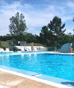 a large swimming pool with blue water and chairs at Los Sauces, adosado a 10 minutos de Oviedo y 15 de Gijon in Llanera