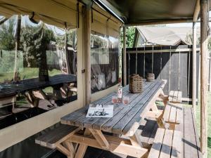 een houten picknicktafel op een afgeschermde veranda bij Charming Woodlodge Stay in Callantsoog