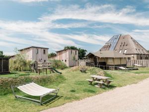 een hangmat en een gebouw met een tent bij Charming Woodlodge Stay in Callantsoog