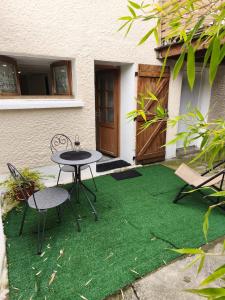 Un patio con una mesa y sillas sobre césped. en Meublé d'affaires et de tourisme, en Aurillac