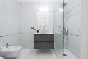 a white bathroom with a sink and a shower at Loft Eleonora D’Arborea in Quartu SantʼElena +13 photos