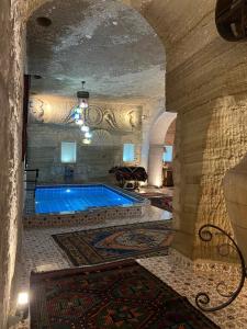 a swimming pool in a large room with a stone wall at Goreme Palace Cave Suites in Göreme