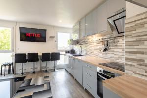 a kitchen with white cabinets and black bar stools at Large 4 Bedroom Apartment near metro - only 30 minutes to Paris and Disneyland in Créteil