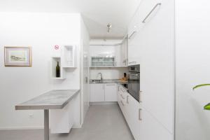 eine weiße Küche mit weißen Schränken und einem Tisch in der Unterkunft Apartment Ema in Split