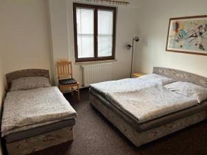a bedroom with two beds and a chair and a window at Apartmán K LANOVCE 10 in Jáchymov +13 photos