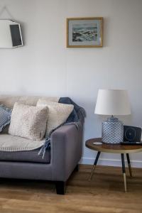 a living room with a couch and a table with a lamp at Kewwater Getaways Seafront Apartment in Johnshaven in Johnshaven