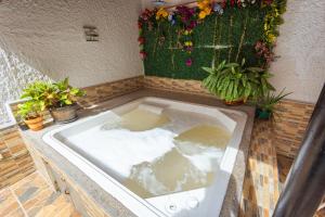 a bath tub filled with water next to potted plants at Hotel Colores Boutique in Medellín