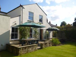 a patio with tables and umbrellas in front of a house at Mickley Bed and Breakfast in Mickley