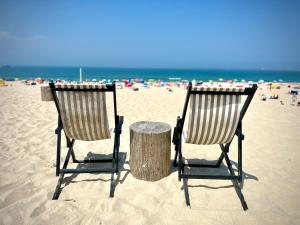 two chairs and a table in the sand at the beach at Moradia exclusiva junto ao mar in Gafanha da Nazaré