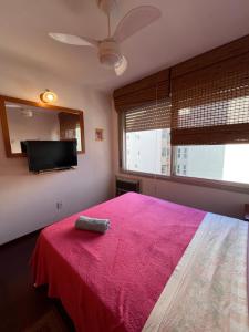 a bedroom with a bed with a pink blanket and a flat screen tv at Flat Embarcadero com camareira in Porto Alegre +28 photos