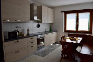 a kitchen with white cabinets and a table in it at Appartamento sole in Isone