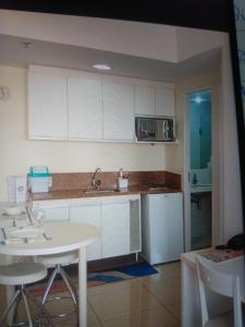 een keuken met witte kasten, een wastafel en een tafel bij Hotel glamuroso in Guarulhos