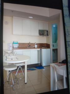 een keuken met witte kasten en een witte tafel en stoelen bij Hotel glamuroso in Guarulhos
