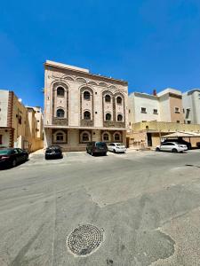 een groot gebouw met auto's geparkeerd op een parkeerplaats bij نورة ريزيدينس in Taif