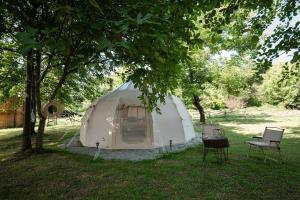 a white tent in a field under a tree at Glamping Riverside Skadar lake in Železnička Stanica Zeta
