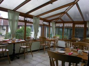 a conservatory with wooden tables and chairs and windows at Six Bells Inn in Bardwell
