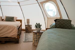 a bedroom with two beds and a round window at Glamping Riverside Skadar lake in Železnička Stanica Zeta