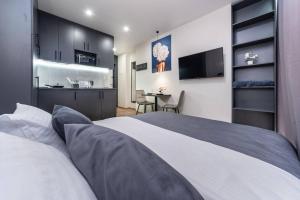 a bedroom with a white bed and a kitchen at Новий Люкс, ЖК Варшавський, Виговського 4012, 5 хв Ретровіль, Вишгород in Kyiv +2 photos