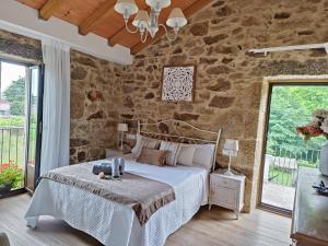 een slaapkamer met een bed en een stenen muur bij A Solaina da Bouza in Cambados +121 foto's