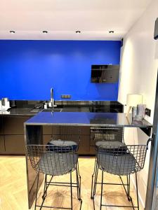 Una cocina azul con tres sillas y un mostrador. en Sur les traces de Cyrano Duplex, en Bergerac