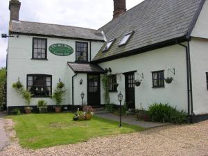 a white building with plants in the front of it at Six Bells Inn in Bardwell