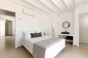 una camera da letto bianca con un letto grande e uno specchio di Ryous st John ad Agios Ioannis